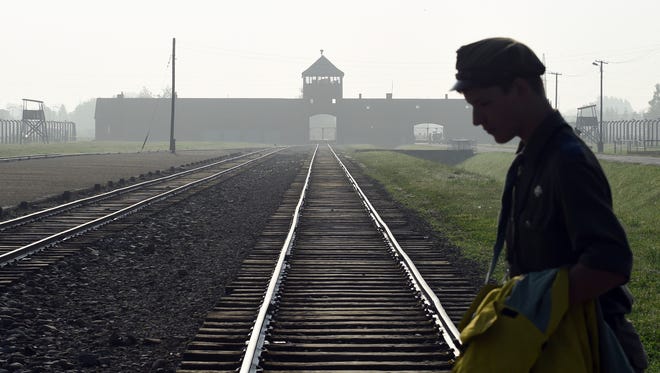 FILE - In this July 29, 2016 file photo a man crosses the rails leading to the former Nazi death camp of Auschwitz-Birkenau prior to a visit by Pope Francis, in Poland.