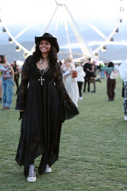 A festivalgoer finishes off her flowy black dress with a cross necklace and high-top sneakers.