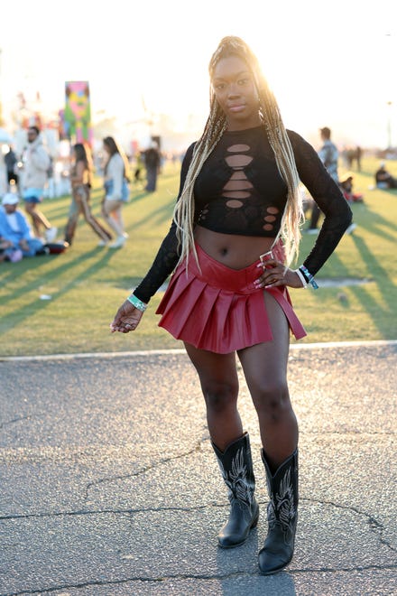 A festivalgoer pairs her ripped crop top with a pleated bright red mini.