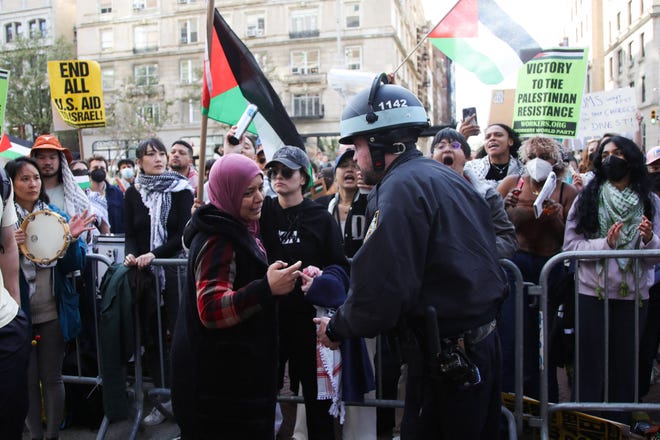 A woman speaks to a police officer as pro-Palestinian activists protest outside Columbia University in New York City on April 20, 2024.