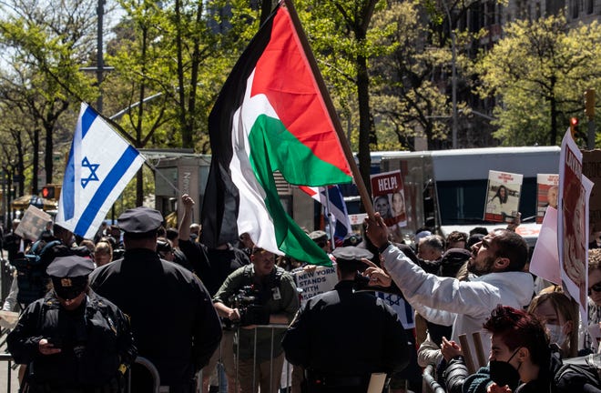 Palestinian and Israeli protestors waved flags as they protested outside the entrance to Columbia University in Manhattan April 22, 2024 after school officials closed the campus and made all classes remote. The protestors were kept separated by the New York City Police Department. This came after hundreds of pro-Palestinian protestors took over large parts of the campus last week.