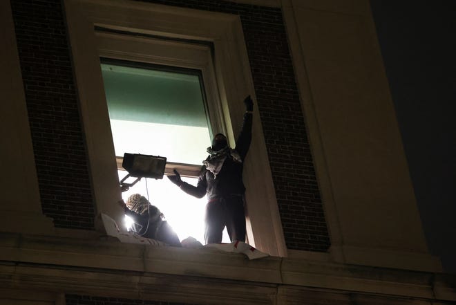 Protesters gesture from a window of Hamilton Hall, after barricading themselves inside the building at Columbia University, after an earlier order from university officials to disband the protest encampment supporting Palestinians, or face suspension in New York City, U.S., April 30, 2024.