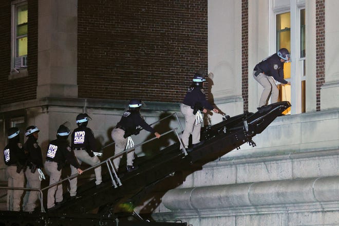 NYPD officers in riot gear break into a building at Columbia University, where pro-Palestinian students are barricaded inside a building and have set up an encampment, in New York City on April 30, 2024. Columbia University normally teems with students, but a "Free Palestine" banner now hangs from a building where young protesters have barricaded themselves and the few wandering through campus generally appear tense. Students here were among the first to embrace the pro-Palestinian campus encampment movement, which has spread to a number of universities across the United States.
