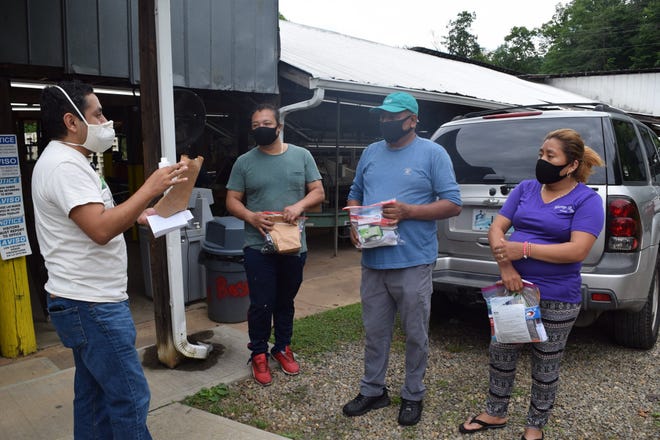 In North Carolina, Latinos account for 44% of all COVID_19 cases although they comprise 9.6% of the population. In this photo, a Vecinos Farmworker Health Program worker talks to workers wearing masks. Ricardo Ball, Vecinos Outreach Worker, talks with workers about masks and other safety measures here.