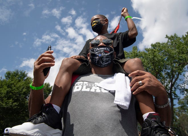 Damien Hudson carries his son Ktaemon Hudson, 7, during the 'Get Off Our Necks' Commitment March on Washington on August, 28, 2020.